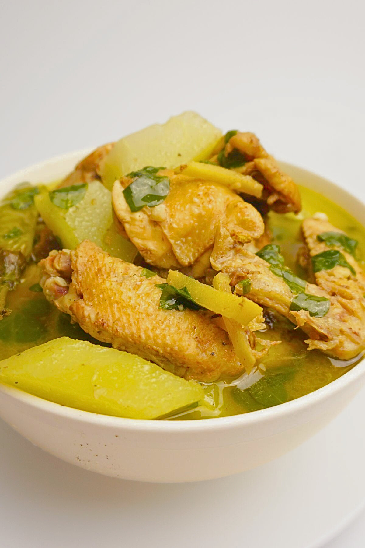 Chicken tinola in a white bowl.