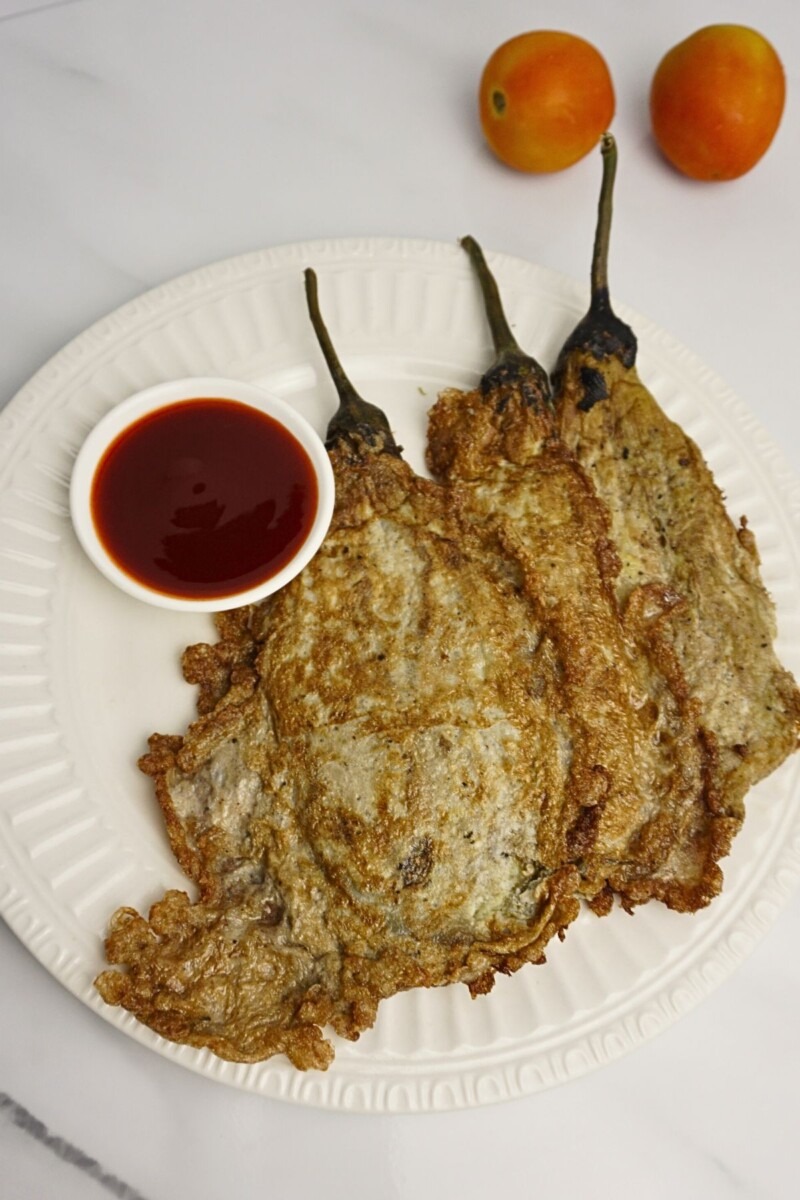 Top view of fried tortang talong with ketchup dip and fresh tomatoes on the side.