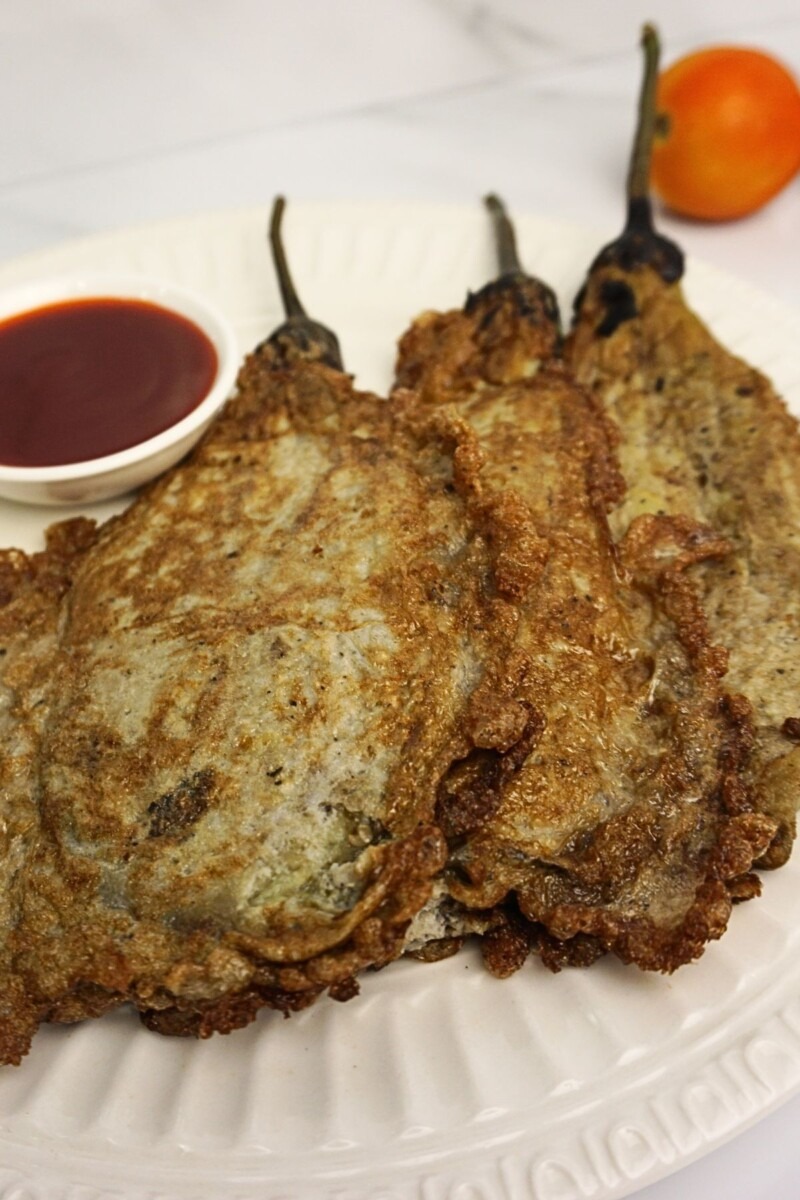Tortang talong in plate with fresh tomato on the side.