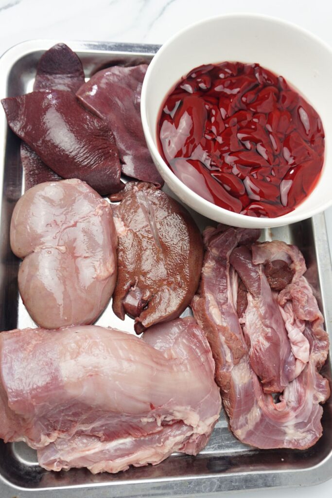 Lean pork, pork spleen, pork kidney, pork liver and pork blood in a stainless tray.