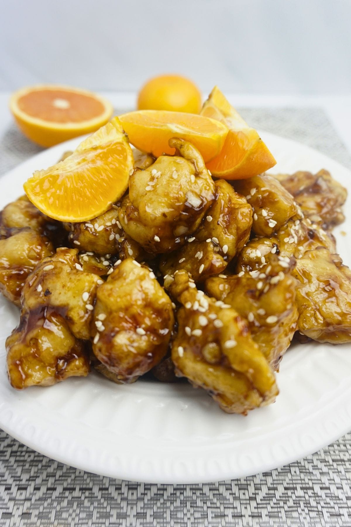 Plate of chicken glazed in orange sauce with fresh oranges on top.