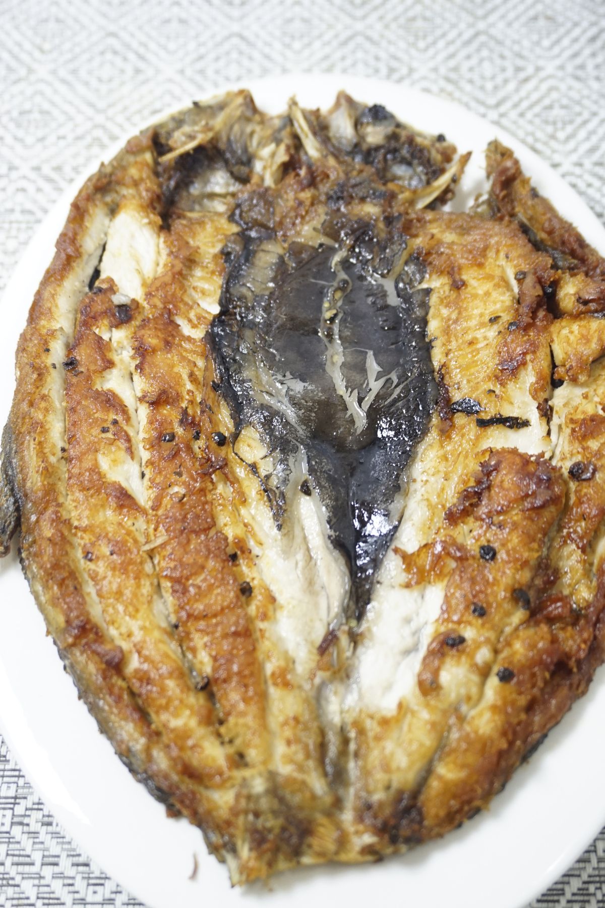 Daing na bangus served in a white plate.